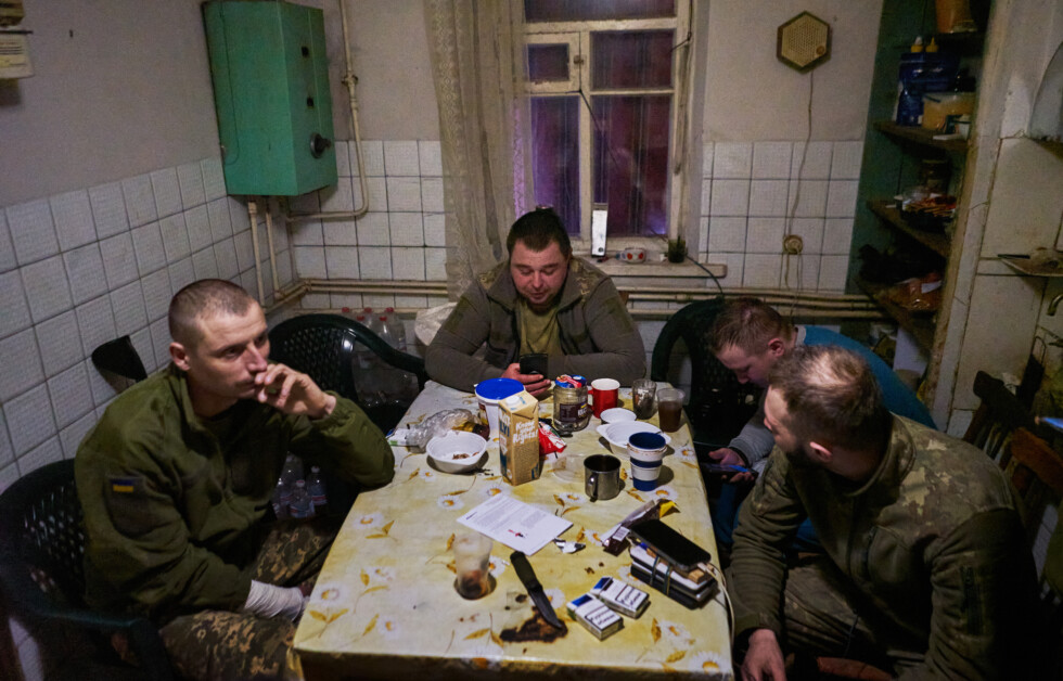 Ukrainian soldiers from 28th Intelligent Company of Knights of the Winter March using their mobile phones while sitting in the kitchen.