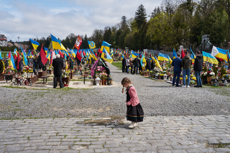 A girl plays with a puddle while her family stay at a grave of its fallen relative who defended Ukraine against Russian army during on Easter Sunday at the Lychakiv Cemetery.